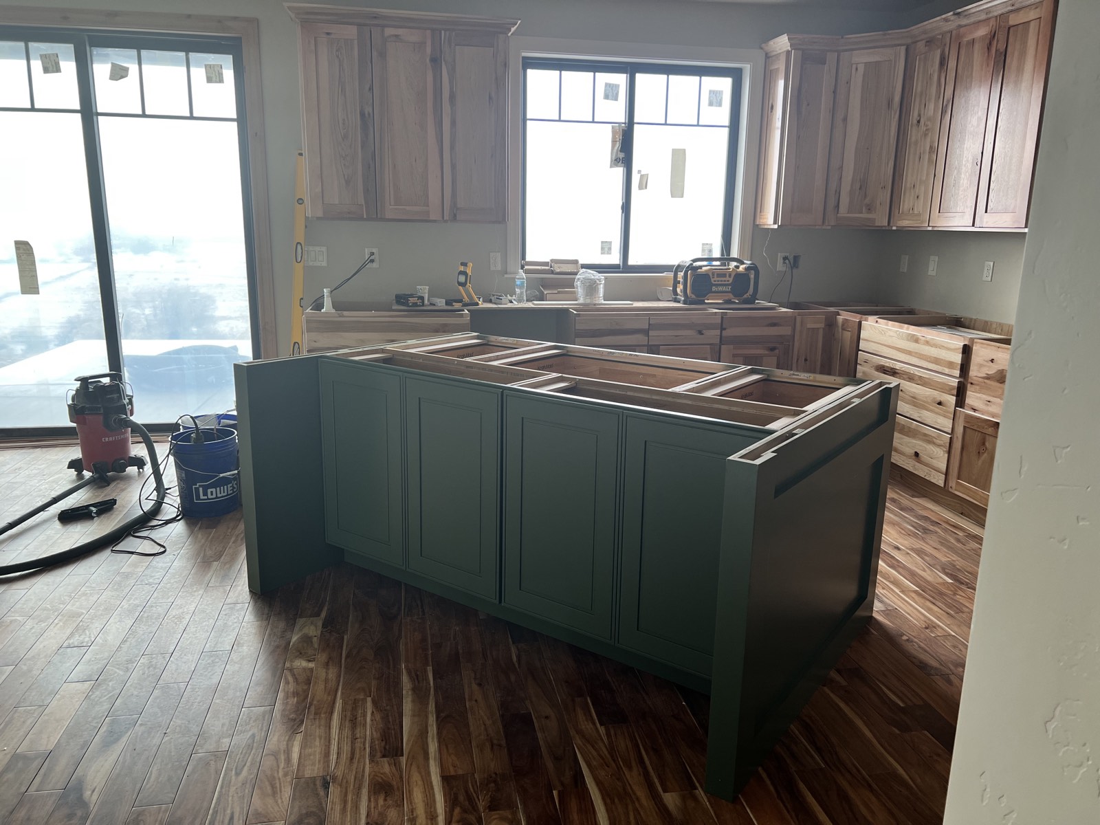 Custom kitchen with green island and hickory cabinetry taking shape